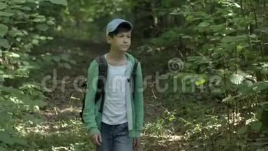 一个带背包的带着帽子的旅行男孩穿过树林四处张望